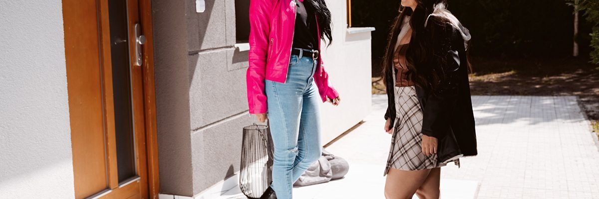 Two beautiful girls in fashionable clothes meet in the street for a date.