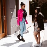 Two beautiful girls in fashionable clothes meet in the street for a date.